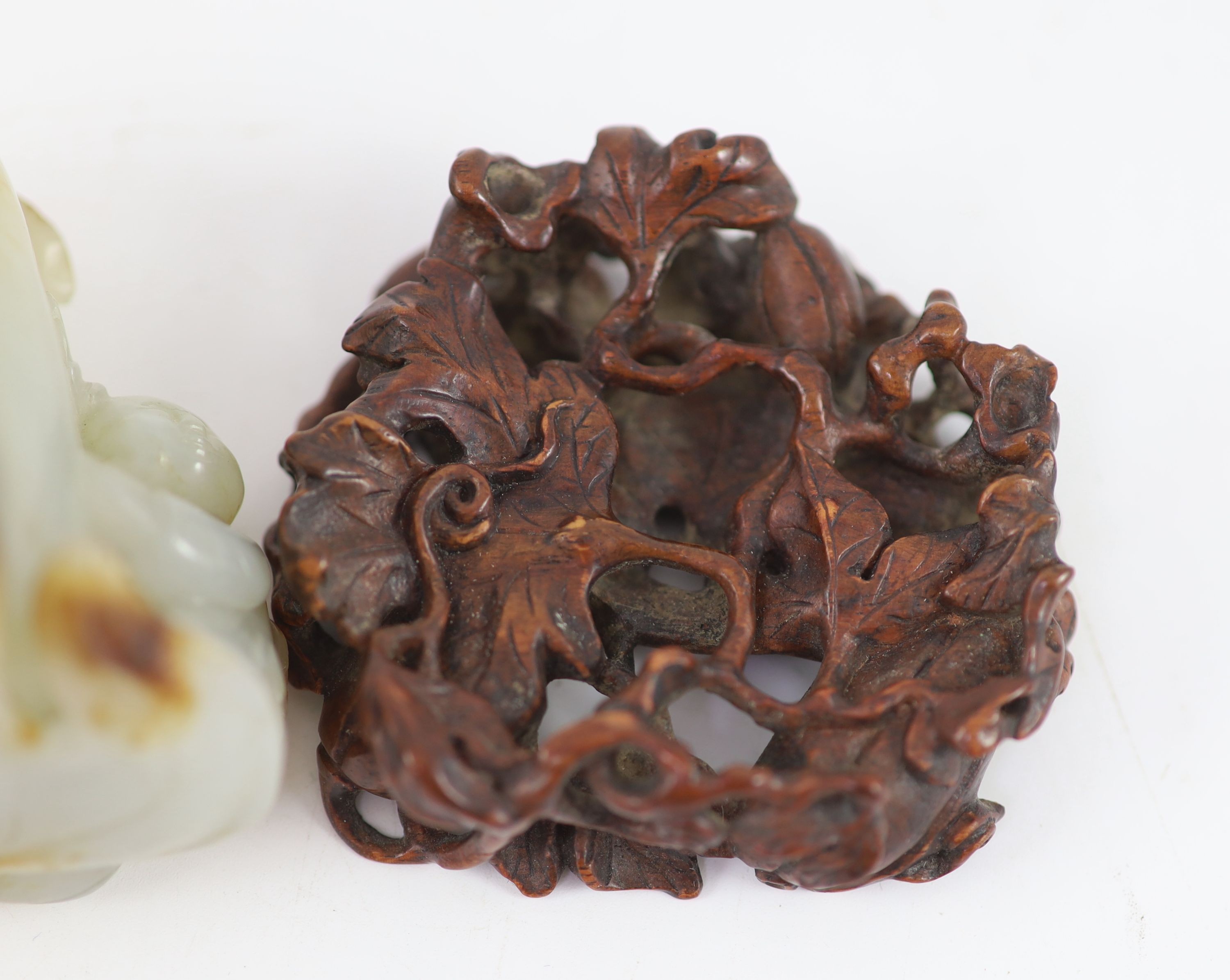 A Chinese pale celadon and russet jade 'boy' jar and cover, 8.3 cm high, the hardwood stand carved as a vine